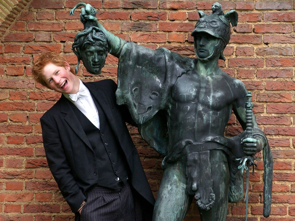 Prinz Harry albert neben einer Bronze-Statue herum.