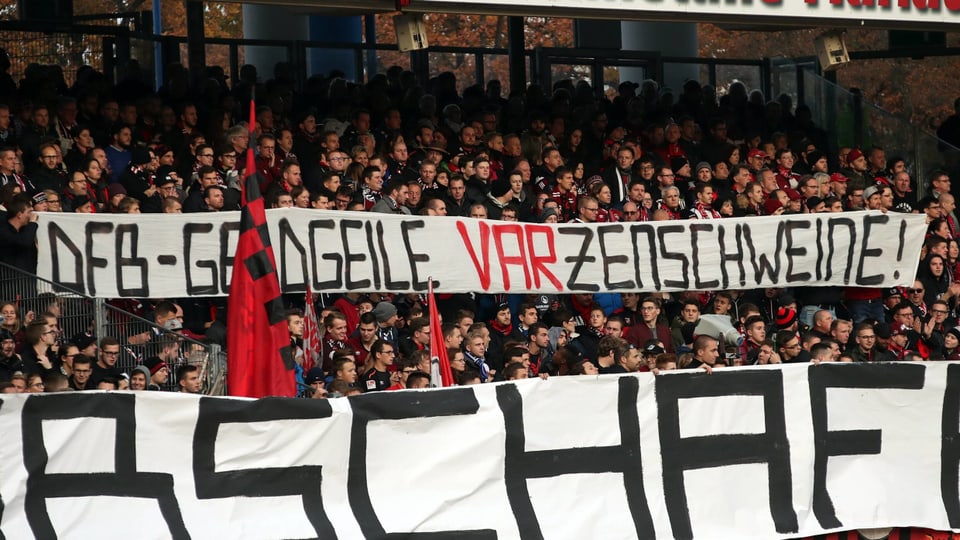 Fans des 1. FC Nürnberg halten ein Plakat mit Kritik am Videobeweis in die Höhe.