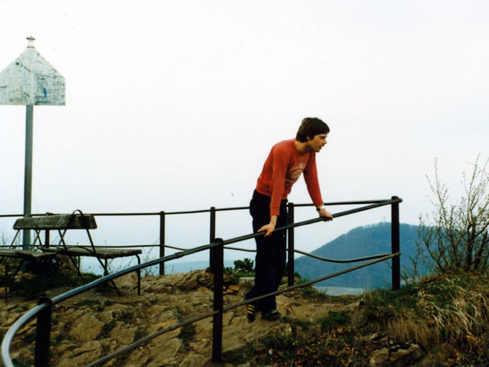 Mann in rotem Pullover schaut von einem Berg hinunter
