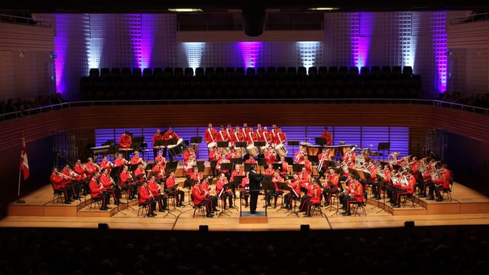 Musikerinnen und Musiker sitzen auf der Bühne und machen Musik.