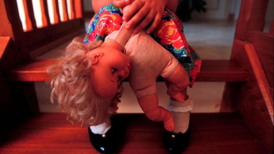 Mädchen sitzt auf einer Treppe mit einer Puppe in der Hand.
