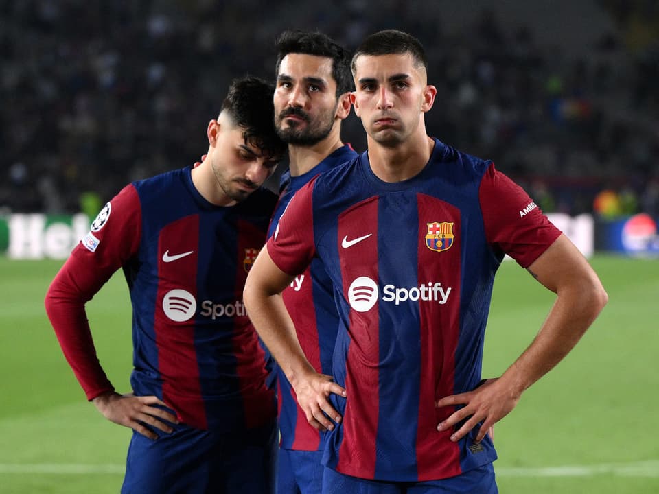 Drei Fussballspieler des FC Barcelona auf dem Spielfeld in Trikots
