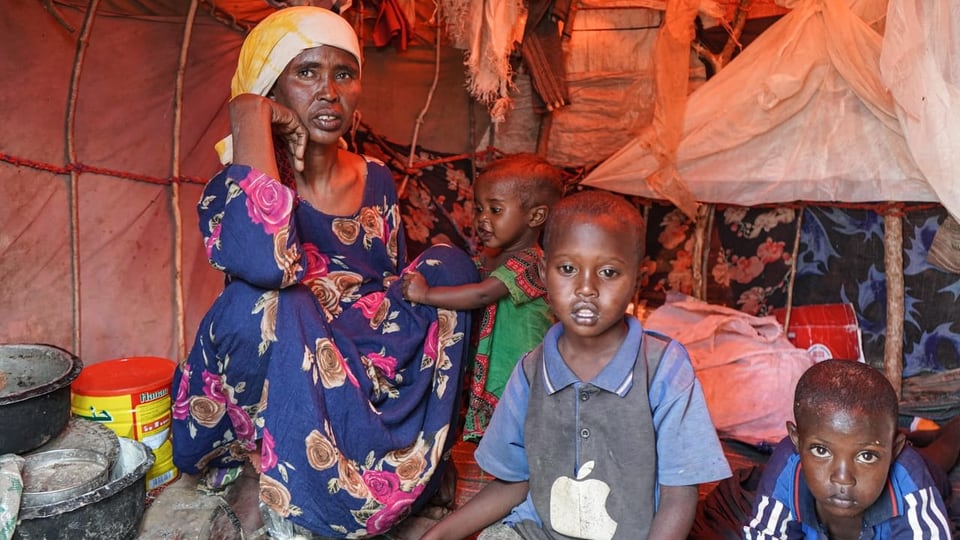 Eine Somali-Frau sitzt mit drei Kindern in einem Zelt.