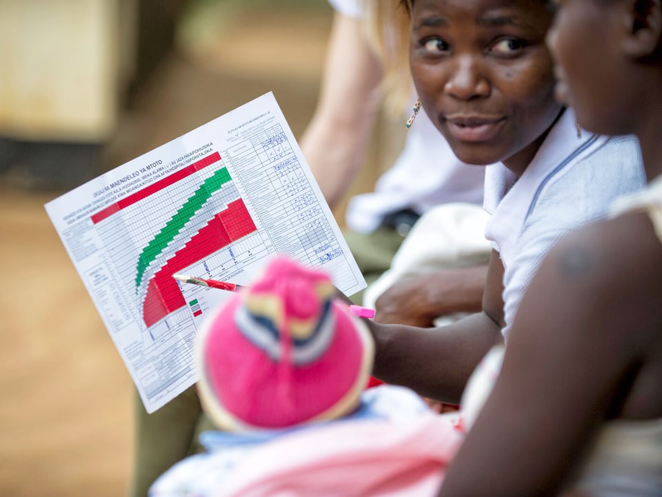 Eine Frau in Tansania hält ein Papier mit Statistiken drauf.