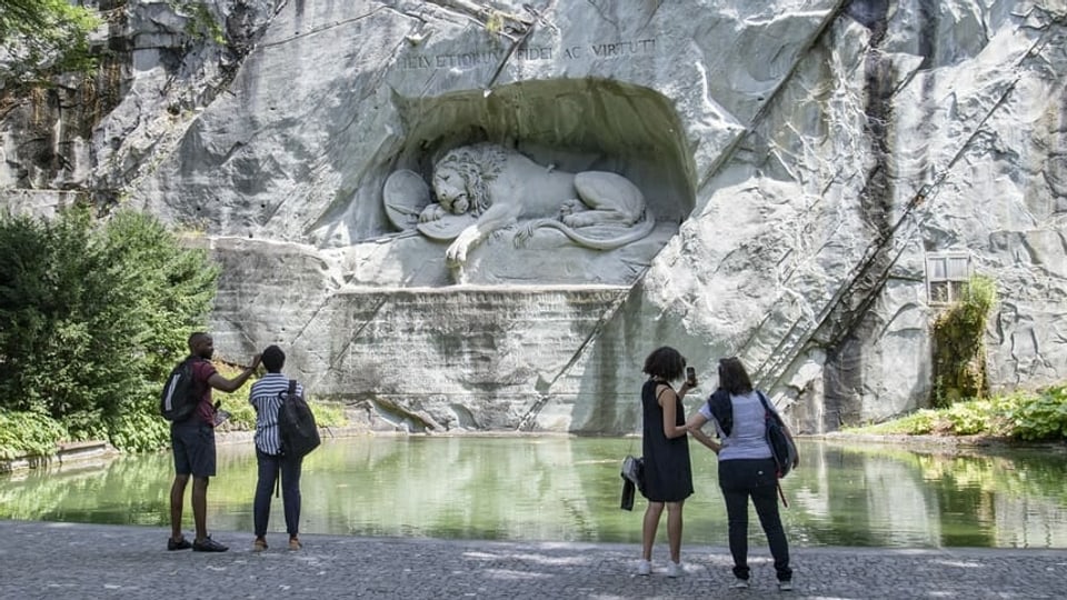 Vier Menschen stehen vor dem Löwendenkmal