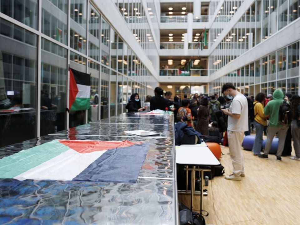 Menschen in einem modernen Gebäude mit einer grossen Flagge auf Tischen.