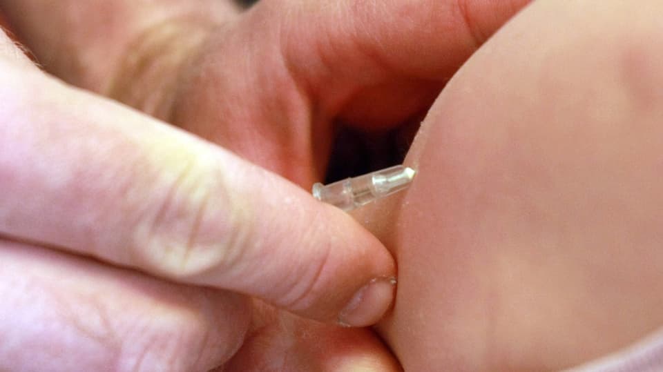Ein Arzt impft ein Kind gegen Masern.