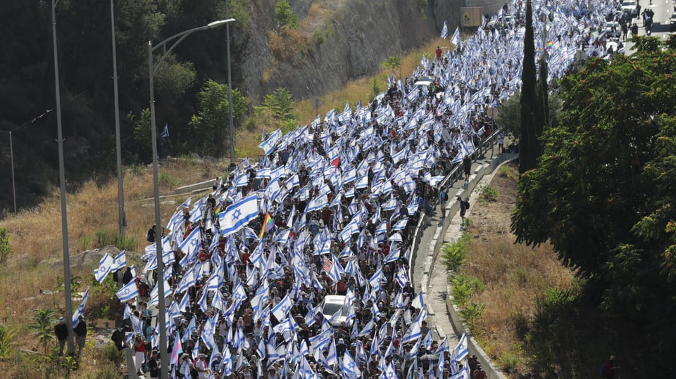 Tausende ziehen mit israelischen Flaggen durch eine Strasse