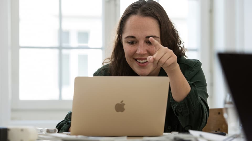 Eine junge Frau sitzt am Laptop.