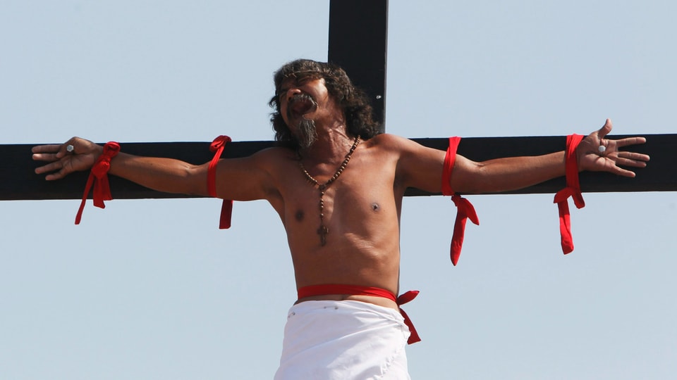 Ein Mann hängt am Kreuz wie Jesus.