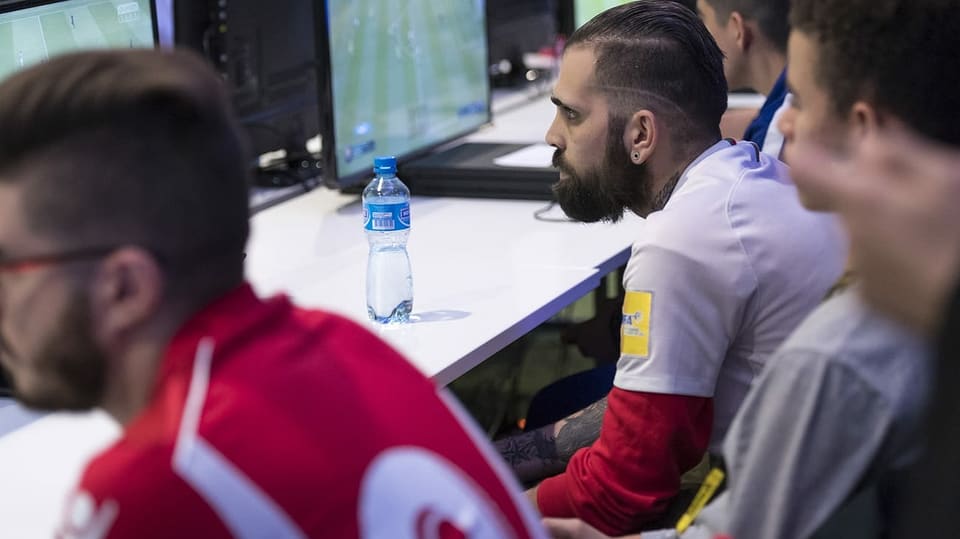 Spieler in Trikots spielen Fifa an den Bildschirmen der Baloise International Gaming Show.