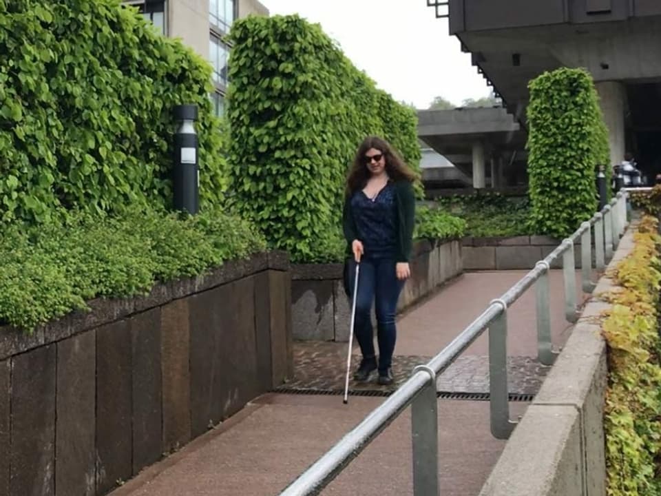 Luana Schena läuft mit ihrem weissen Stock eine Rampe auf dem Campus der Uni runter.