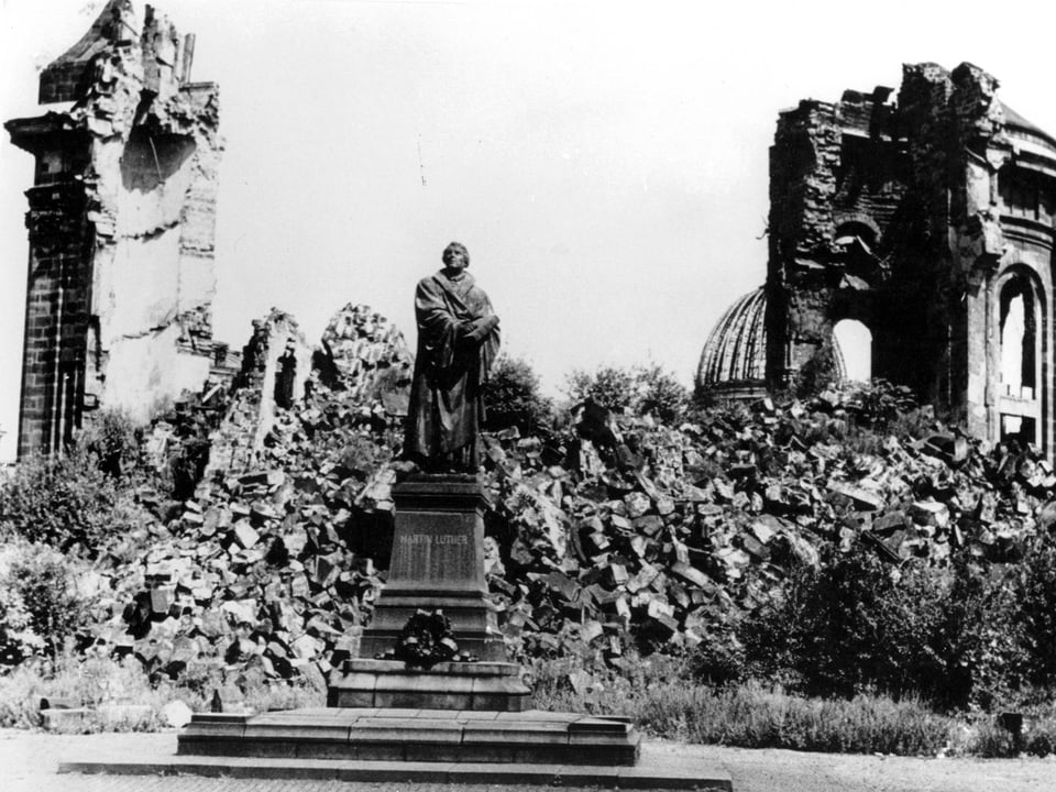 Statue vor zerstörtem Gebäude.