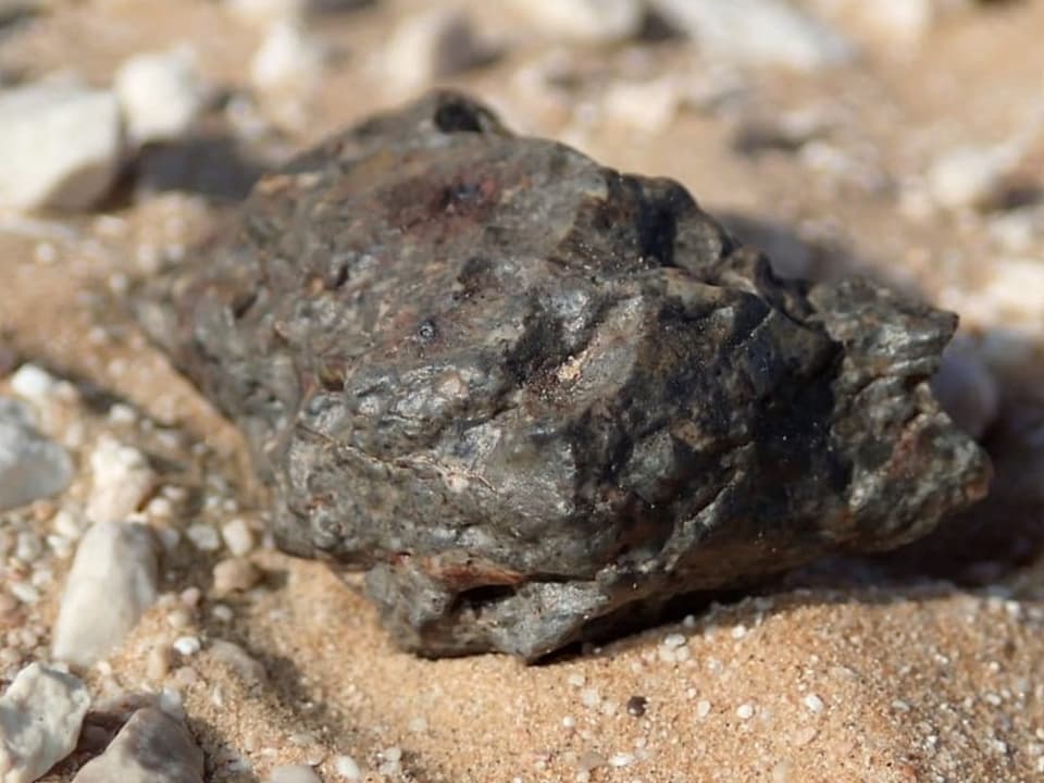 Ein Stück Mond liegt auf Sand.