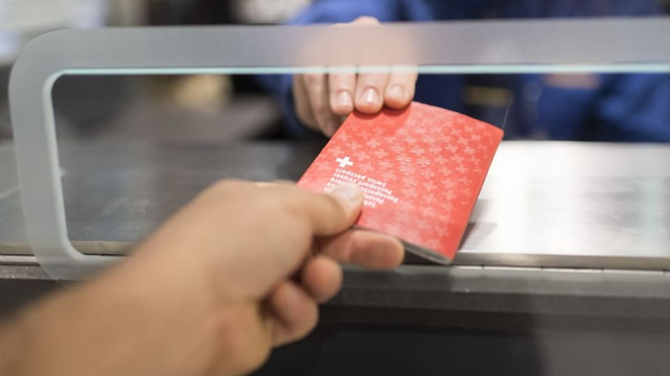 Person gibt Beamte an Flughafen den Schweizer Pass zur Personenkontrolle.