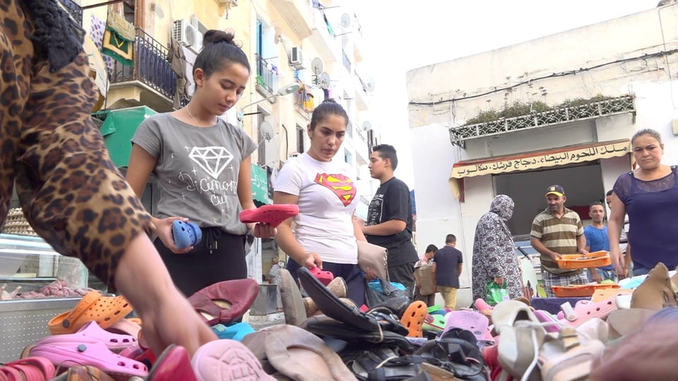 Frauen schauen Schuhe an auf einem Markt in Tunis. 