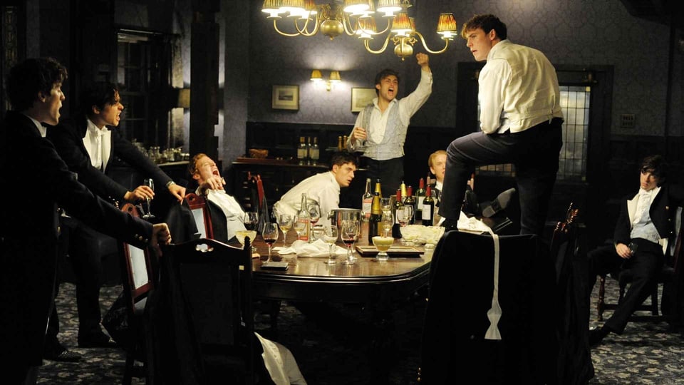 Bild aus dem Film Riot Club, Studenten besoffen auf dem Tisch
