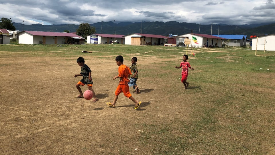 Kinder spielen Fussball in einem Barackenlager in Palu. 