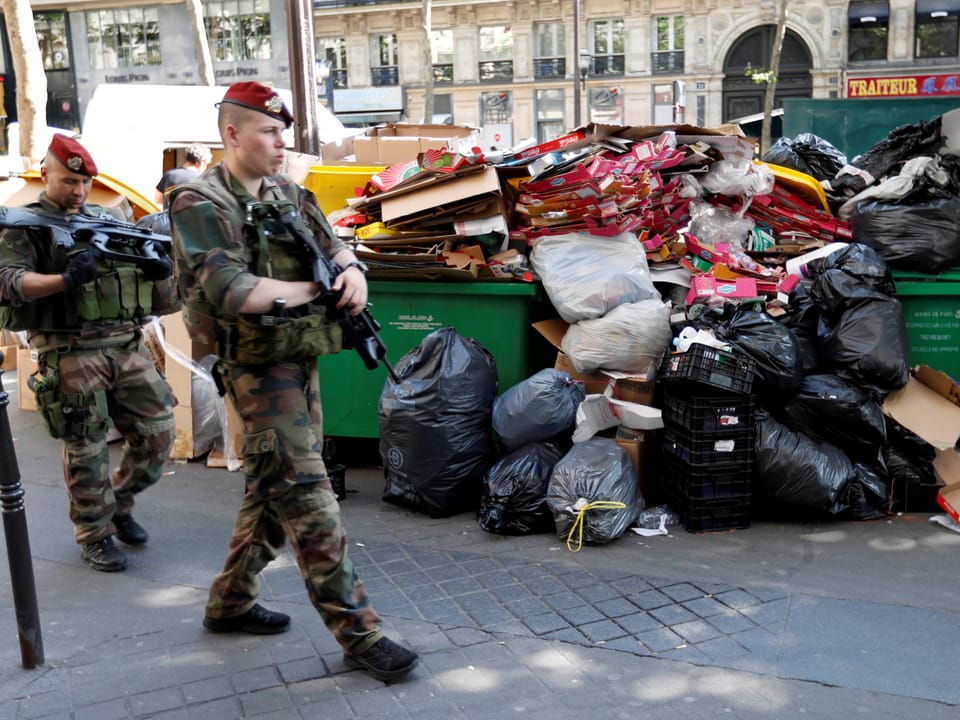 Soldaten vor einem Müllberg.