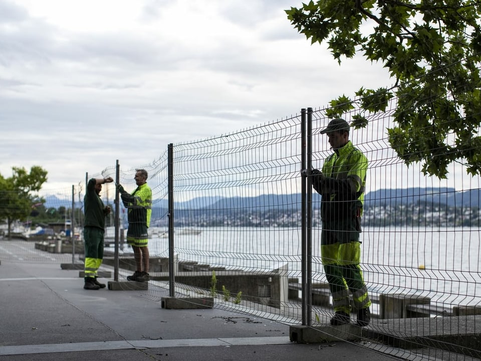 Mitarbeiter der Stadt entfernen die Absperrgitter rund um das Zürcher Seebecken. 