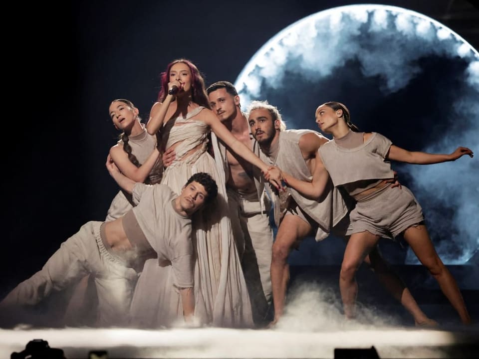 Sängerin performt mit Tänzern auf der Bühne vor einem grossen Mond.