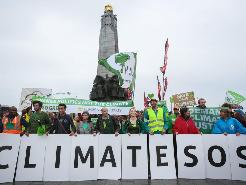 Protestierende halten ein Banner mit einer SOS-Notruf für den Klimaschutz hoch