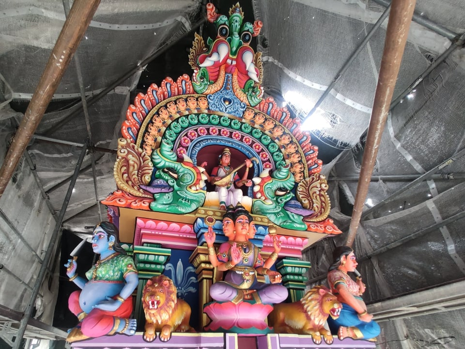 Spitze eines Hindutempels mit vielen farbigen Figuren.
