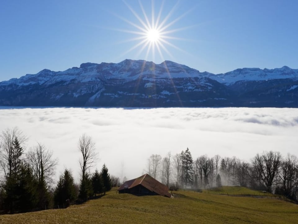 Nebelmeer mit Sonne in den Bergen darüber.