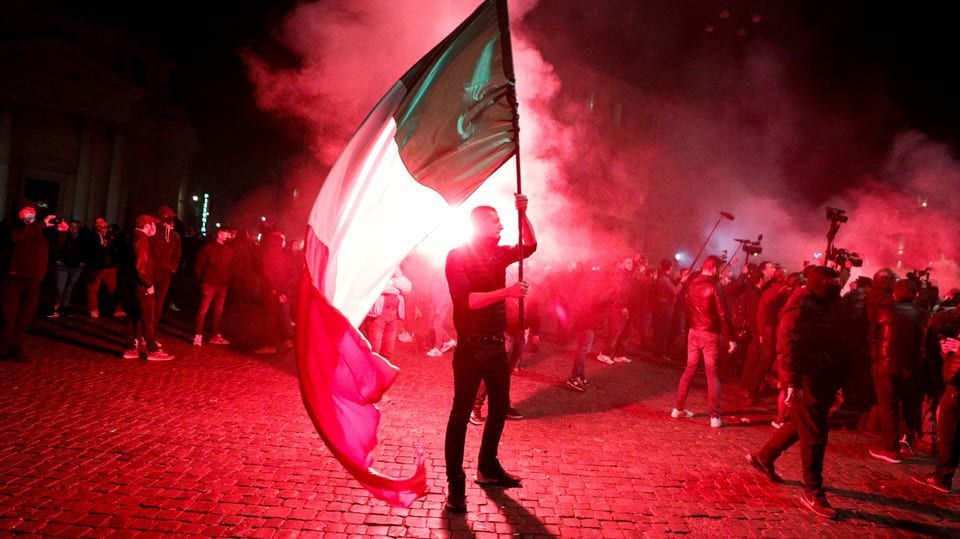 Protestierende mit Italien-Fahnen im Schein von roten Signalfackeln.