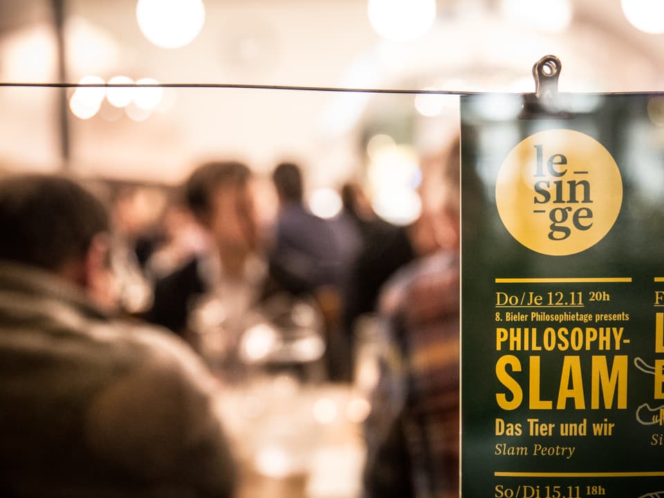 Blick in ein Restaurant, davor Plakat mit Hinweis auf den Philo-Slam