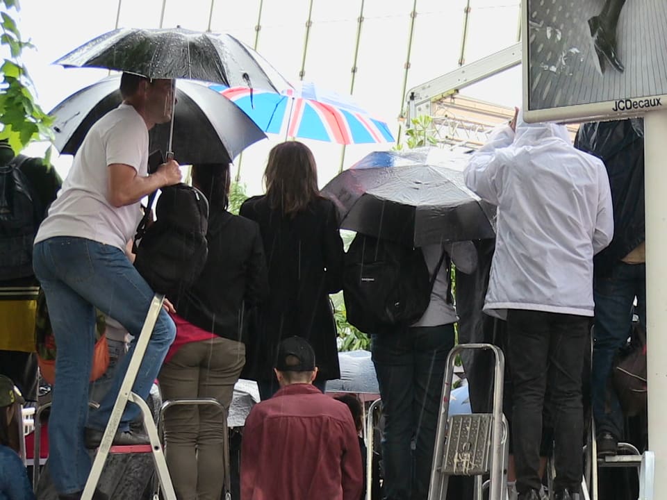 Fans stehen mit Regenschirmen am Roten Teppich in Cannes.
