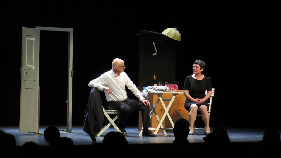 Zwei Menschen auf der Bühne, Publikum im Vordergrund (im Schatten)