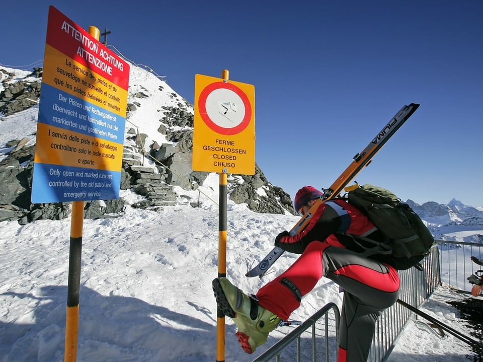 Ein Skifahrer steigt über eine Abschrankung.