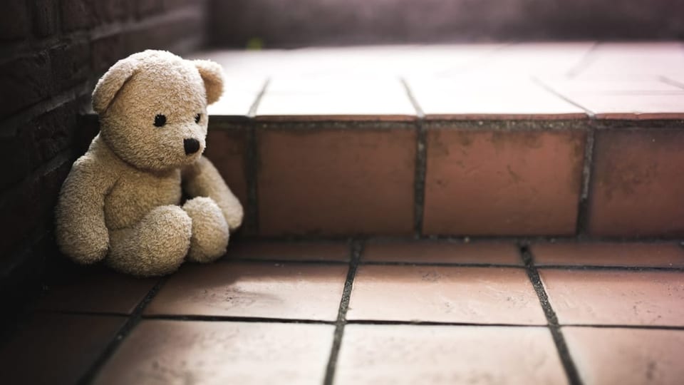 Ein trauriger Teddybär sitzt auf einer Treppe
