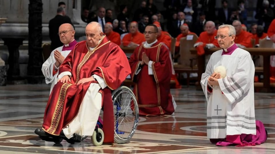 Franziskus in rotem Gewand und im Rollstuhl.