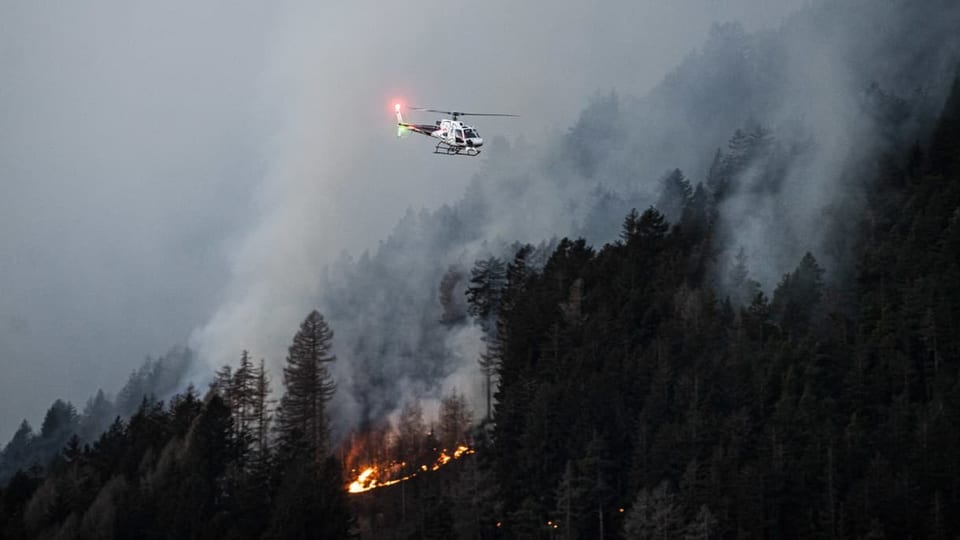 Löschhelikopter über einem brennenden Waldstück