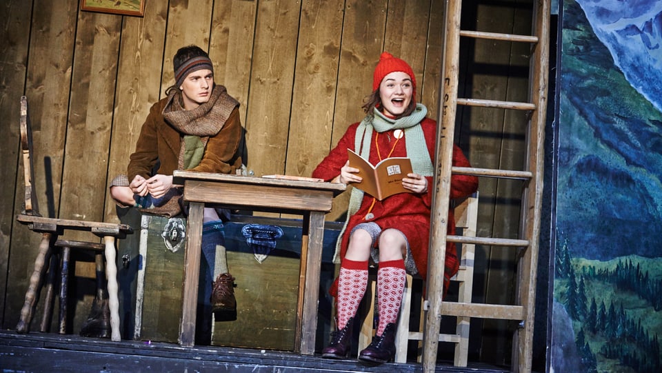 Ein Junge und ein Mädchen sitzen an einem Holztisch. 