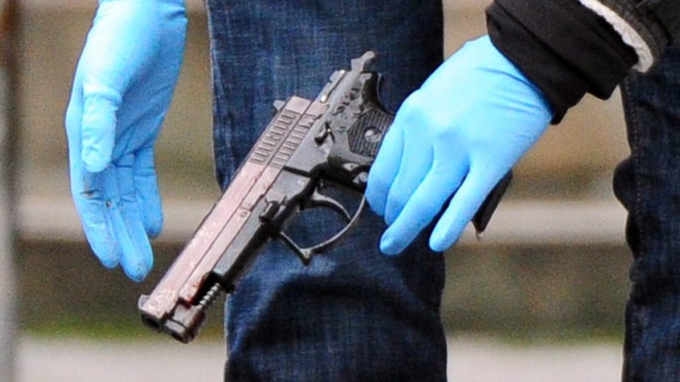 Eine Beamtin mit Handschuhen hält die vermeintliche Tatwaffe in Händen.