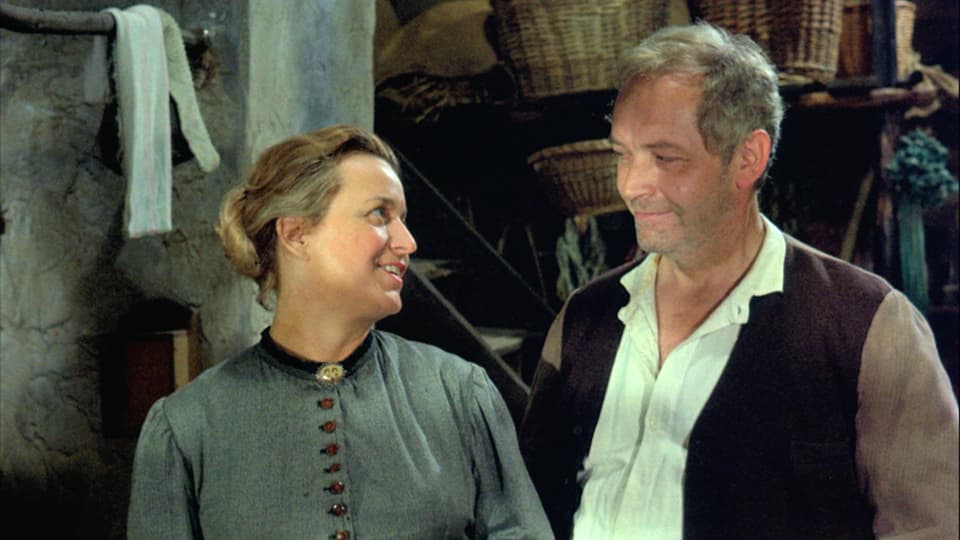 Ein Mann und eine Frau in bäuerlicher Kleidung stehen in einem Raum und schauen sich an.