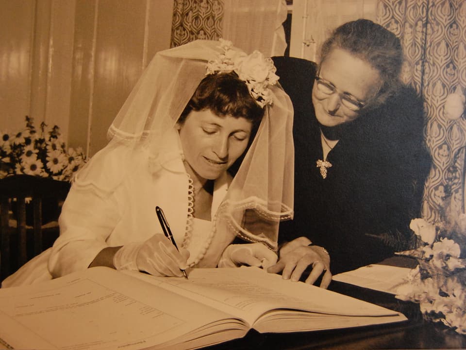 Eine Braut unterschreibt im Hochzeitsbuch.