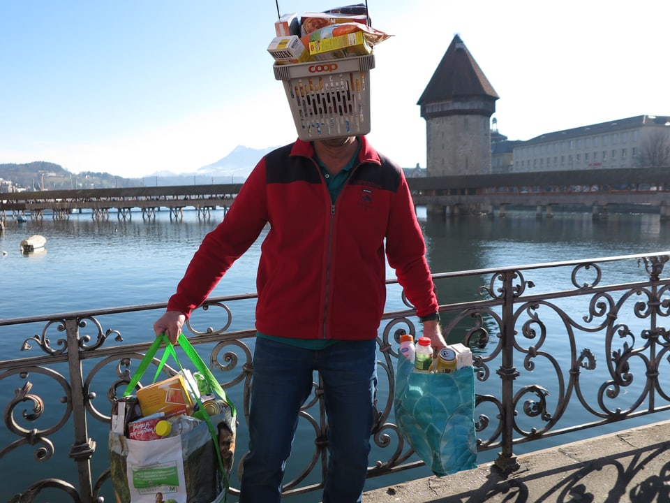 Ein Fasnächtler vor dem Luzerner Wasserturm als Schnäppchenjäger unterwegs mit vollen Taschen und Körben. 