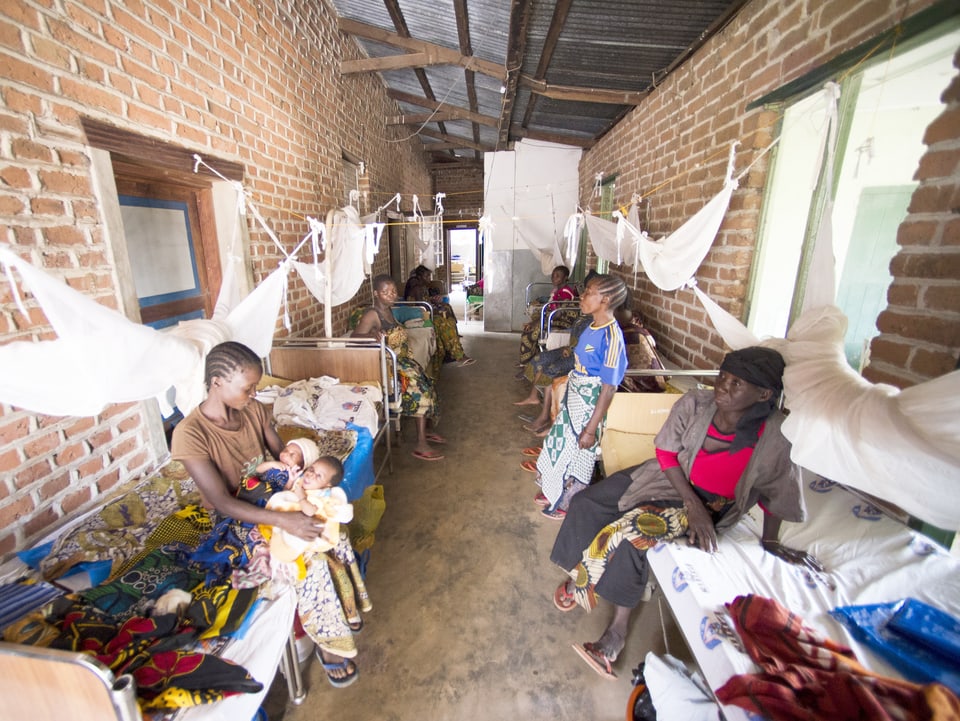 Frauen sitzen in Tansania in einer Geburtsabteilung, die rudimentär eingerichtet ist.