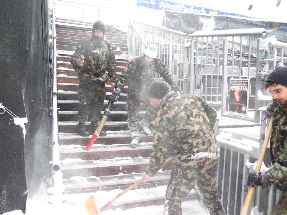 Männer befreien die Tribüne vom Schnee.