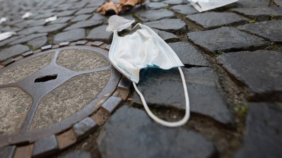 Weisse Maske lieigt am Boden auf Kopfsteinpflaster