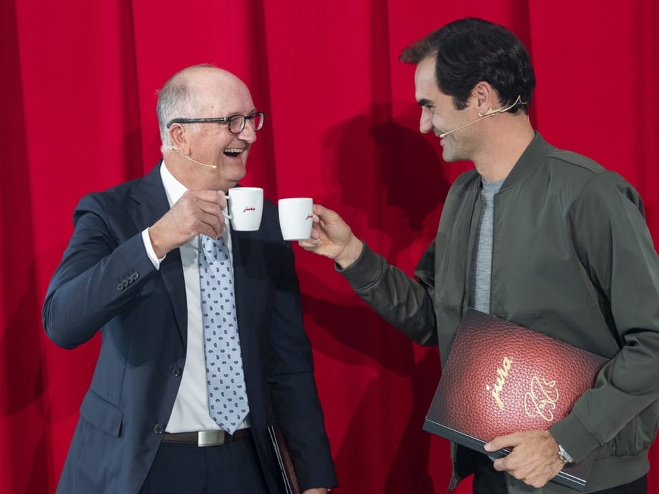 Roger Federer und Emanuel Probst stossen mit zwei Jura-Kaffeetassen an.
