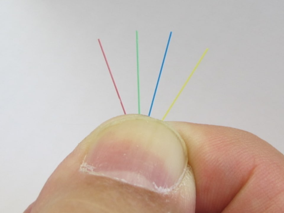 Die winzigen Glasfaserkabel sind dünner als Haare. Im Bild vier Kabel, wovon jedes noch einzeln durch eine Ummantelung geschützt wird.