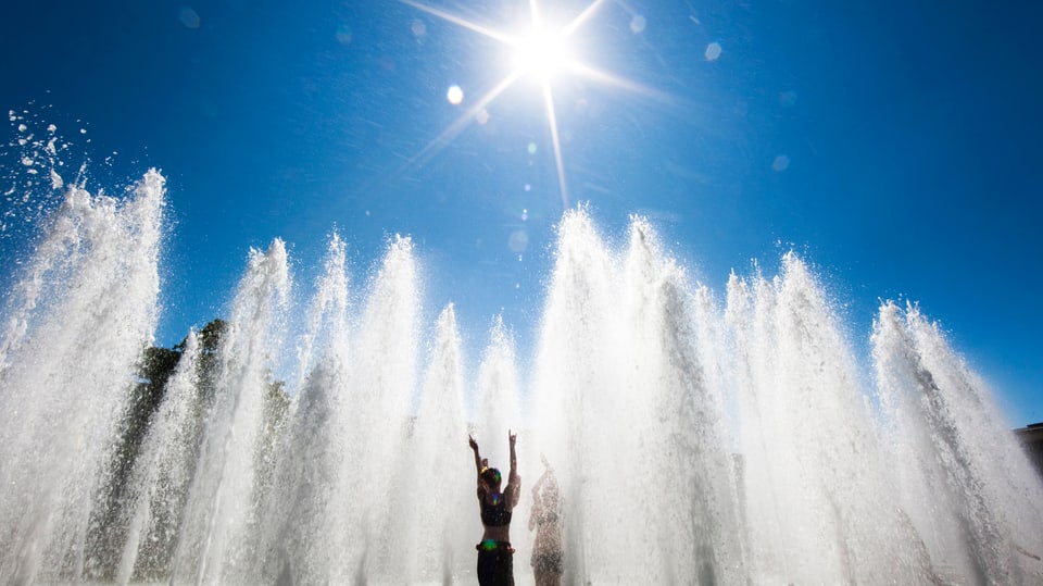 Person in der Sonne in einem Springbrunnen.
