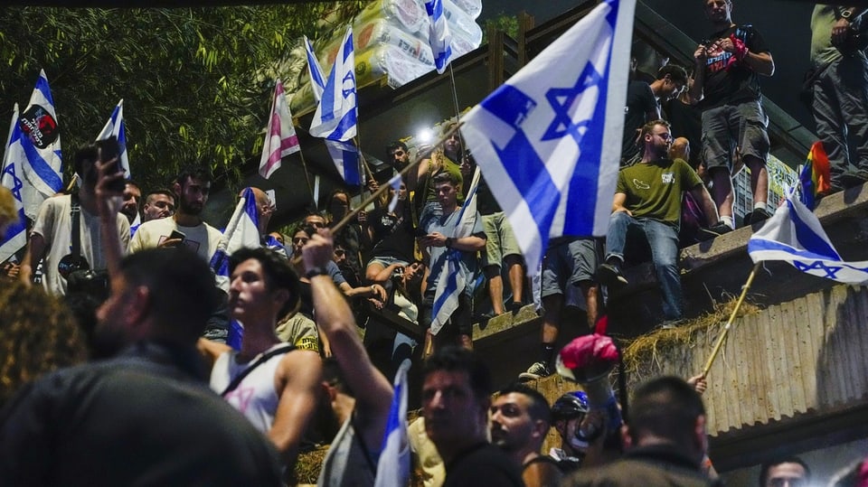 Menschen blockieren eine Strasse und schwenken Israel-Fahnen