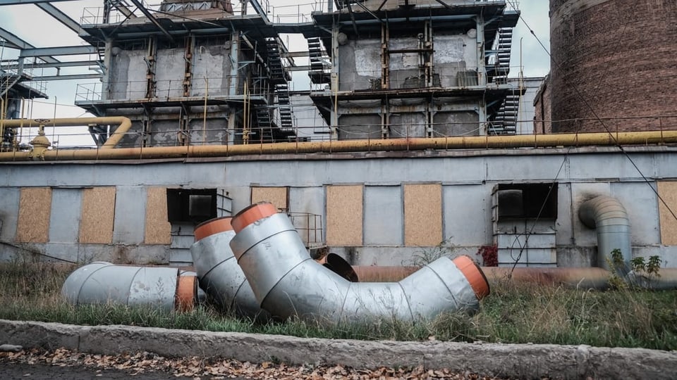 Drei grosse Rohre liegen vor einem Elektrizitätswerk in Charkiw