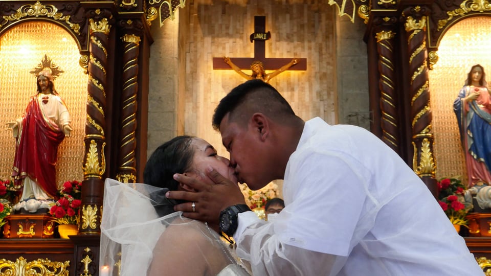 A Filipino couple kisses at their wedding ceremony.